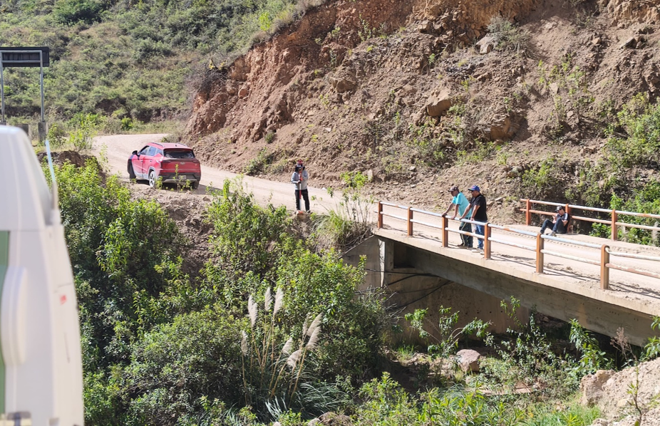 Personal en campo junto a un puente y una vía en zona rural